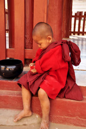 Burmese novice playing money of receive donate from burma people and foreign travelers visit respect praying at Shwezigon Pagoda Paya temple at Bagan or Pagan on February 2, 2013 in Mandalay, Myanmarのeditorial素材