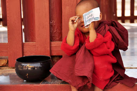 Burmese novice playing money of receive donate from burma people and foreign travelers visit respect praying at Shwezigon Pagoda Paya temple at Bagan or Pagan on February 2, 2013 in Mandalay, Myanmarのeditorial素材