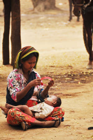 Burmese mother and son daughter baby beggar sitting and begging money from burma people and foreign traveler travel visit at Bagan or Pagan ancient city on February 2, 2013 in Mandalay region, Myanmarのeditorial素材
