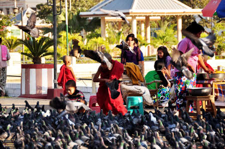 Burmese children boys novice group travel visit playing with dove bird and feeding food to pigeon birds at garden park of Mahamuni Paya Pagoda Temple on February 4, 2013 in Mandalay, Myanmar or Burmaのeditorial素材