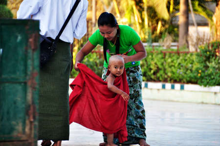 Burmese children novice and mother family travel visit respect praying ancient tradition ritual Maha Myat Muni Buddha statue at Mahamuni Paya Temple on February 3, 2013 in Mandalay, Myanmar or Burmaのeditorial素材