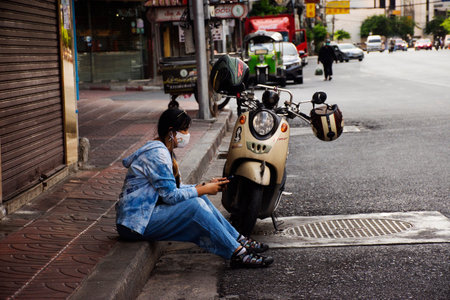 Life lifestyle new normal of thai women sitting rest with classic vintage retro motorcycle beside Yaowarat road while lockdown on July 31, 2021 in Bangkok, Thailandのeditorial素材
