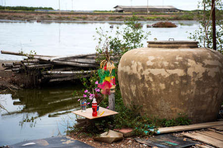 Thai farmer people respect praying give oblation sacrifice to lord guardian spirit of saltland field or local god of saline farmland in local small shrine at Amphawa city in Samut Songkhram, Thailandの写真素材