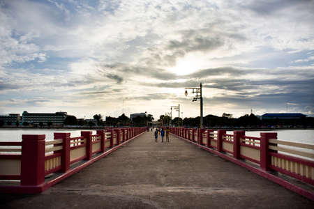 Thai people and foreign travelers travel visit rest relax and exercise playing sport on Saphan saranwithi red bridge sunset at Prachuap bay beach on September 6, 2021 in Prachuap Khiri Khan, Thailandのeditorial素材