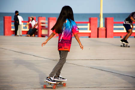 Thai people foreign travelers travel visit rest relax and exercise playing sport skateboard on Saphan saranwithi red bridge at Prachuap bay beach on September 6, 2021 in Prachuap Khiri Khan, Thailandのeditorial素材