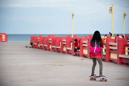 Thai people foreign travelers travel visit rest relax and exercise playing sport skateboard on Saphan saranwithi red bridge at Prachuap bay beach on September 6, 2021 in Prachuap Khiri Khan, Thailandのeditorial素材