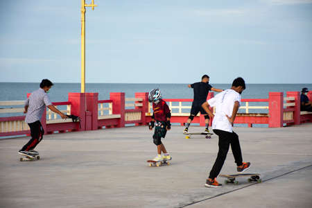 Thai people foreign travelers travel visit rest relax and exercise playing sport skateboard on Saphan saranwithi red bridge at Prachuap bay beach on September 6, 2021 in Prachuap Khiri Khan, Thailandのeditorial素材
