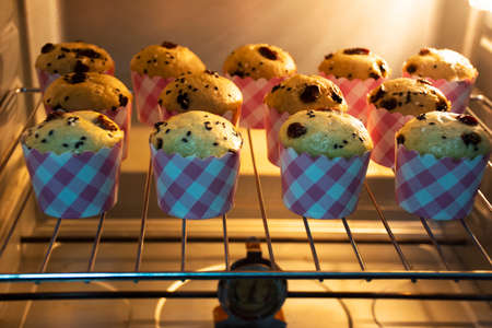 Chef bakery thai people cooking baked cake bananaes cup cake topping chocolate chip bake in electric oven in workshop home for eat and sale at Nonthaburi province of Thailandの写真素材