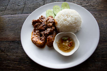 Thai chef cooking food fusion style cuisine fried pork mix mala spicy seasoning sichuan sauce with steamed rice topping vegetables on ceramic dish plate at restaurant cafe shop in Bangkok, Thailandの写真素材