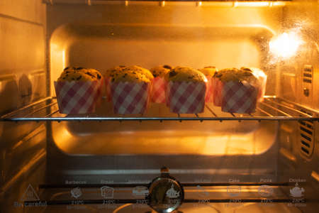 Chef bakery thai people cooking baked cake bananaes cup cake topping chocolate chip bake in electric oven in workshop home for eat and sale at Nonthaburi province of Thailandの写真素材