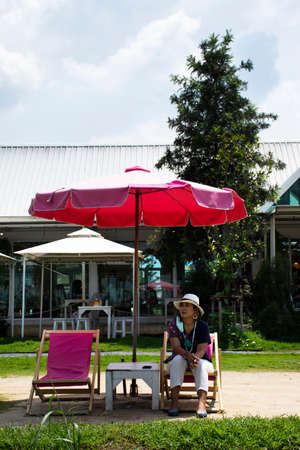 Asian travelers thai women people travel visit and sitting rest relaxed on deck chairs or lounge chair on small beach in garden park outdoor of cafe restaurant coffee shop at Bangkok of Thailandの写真素材