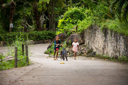 Thai girl and sisters people walking relax and biking bicycle on street at Baan Huay Nam Sai rural countryside village valley hill of Suan Phueng District on November 1, 2021 in Ratchaburi, Thailandのeditorial素材