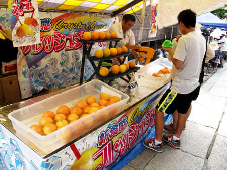 Japanese old men vendor use machine make and sell fresh orange juice for travelers people travel visit eat drink on Hanamikoji street market of Gion old town at Kyoto on July 11, 2015 in Kansai, Japanのeditorial素材
