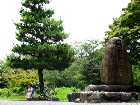 Japanese old man people travel visit and riding or biking bike stop sit resting at garden park with stone monument of Arashiyama place of scenic beauty.at Kyoto city on July 11, 2015 in Kansai, Japanのeditorial素材