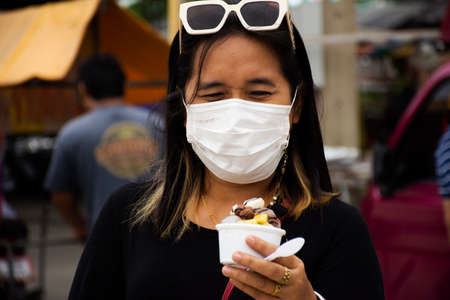 Travelers thai women people travel visit and eating drinking sweet food icecream from food truck at Wat Pracha Rat Bamrung or Rang Man temple at Kamphaeng Saen in Nakhon Pathom, Thailandの写真素材