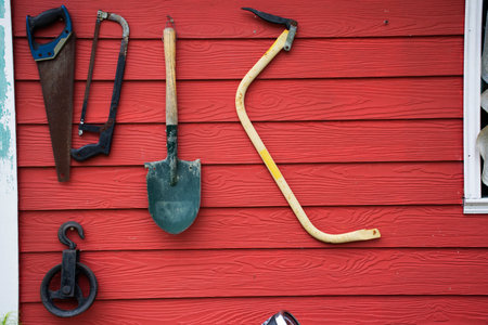 Tools and equipments farm gardening on red wooden wall of barn farmhouse for farmer use growing cultivating horticulture at meadow rural countryside in Nonthaburi, Thailandの写真素材