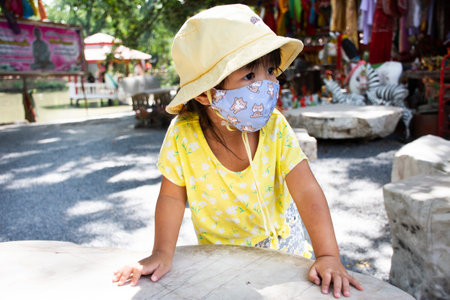Life lifestyle new normal of thai little cute children girl wear fabric mask  for protect COVID 19 outbreak playing on garden park in Wat Thap Kradan temple on November 3, 2022 in Suphan Buri Thailandのeditorial素材