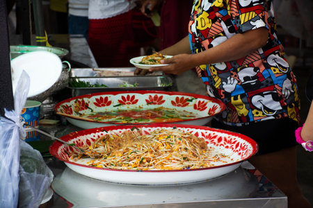 Traditional local thai street food Pad Thai stir fried rice noodles with egg and vegetable mix spices sauce in almshouse for served guest join Kathin ceremony at Wat BangRakYai in Nonthaburi, Thailandの写真素材