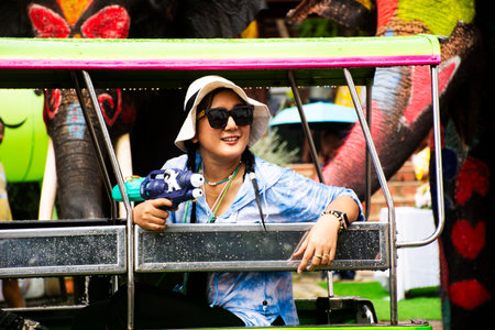 Thai women people traveler travel visit playing splashing or water fights on Froggy Pedicab auto rickshaw with animal elephants in Songkran Festival or Celebration thai new year in Ayutthaya, Thailandの写真素材