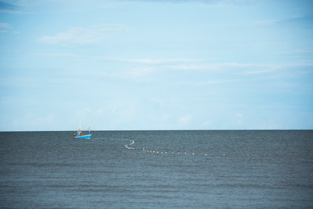 Thai fisher man people sailing wooden fishing boat to trawl laying fish net or drive wood fishery ship for trawling net catch fish marine life at Phetburi Beach in sea ocean in Phetchaburi, Thailandの写真素材
