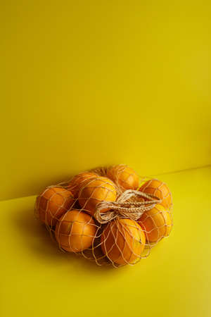 Ripe oranges on a yellow background. Oranges In Reusable Bag.の写真素材