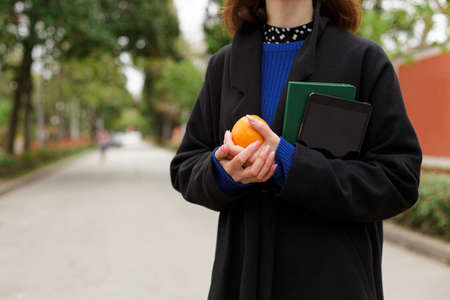 A girl holds a string bag with oranges and a notebook standing on the streetの写真素材