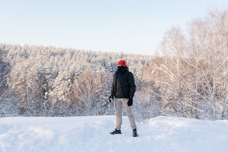 A young man enjoys a winter day on the background of a snow-covered forest
