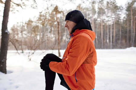 Portrait of a man stretching in the park on a beautiful snowy winter day