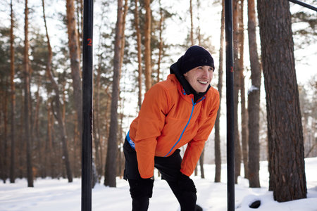A young man is engaged in a workout on a sports field on a winter day