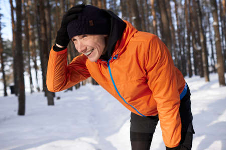 A young man in bright sports clothes enjoys a jog in the woods on a winter day