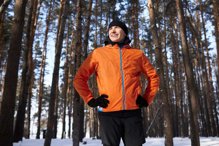 A young man in bright sports clothes enjoys a jog in the woods on a winter day
