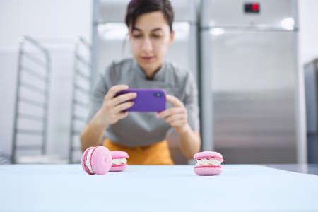 Young girl takes pictures of bright macaroons