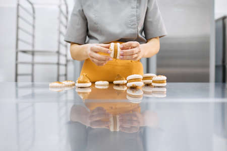 A young girl holds fresh cakes and macaroons in her hands