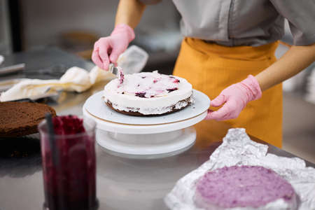 A bright pastry chef girl is engaged in the preparation of a cake