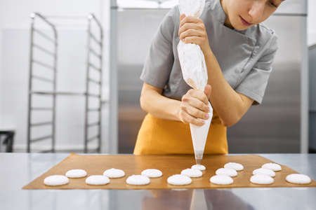 Pastry chef girl prepares fresh cakes at her small production facility