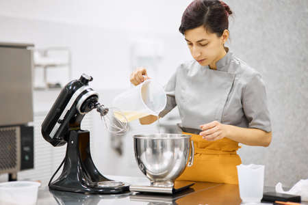 A bright girl cooks sweet dishes at a small production facility