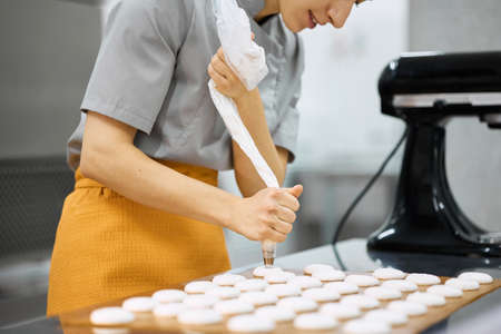 Pastry chef girl prepares fresh cakes at her small production facilityの写真素材