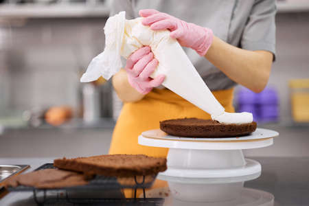 A bright pastry chef girl is engaged in the preparation of a cake