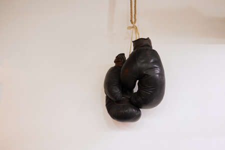 Black boxing gloves hang on a light wall