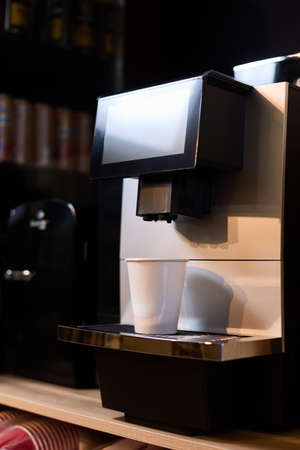 A paper cup of coffee is on the coffee machine