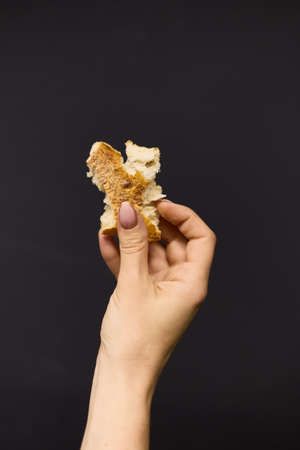 Womens hands break off a piece of fresh bread, close up