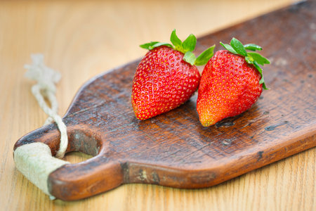 Strawberries on a wooden cutting board on a wooden background.の写真素材