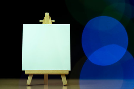 Blank white canvas on wooden easel with bokeh backgroundの写真素材