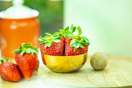 Strawberry in a golden bowl on a wooden table, selective focusの写真素材