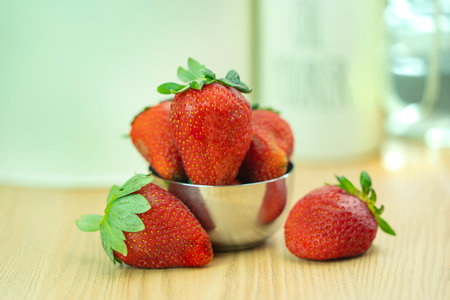 Strawberries in a metal bowl on a wooden table, selective focusの写真素材