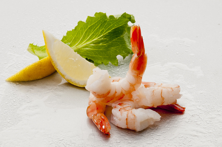 Steamed Jumbo headless shrimps with deli leaves and Lemon on white plate on white backgroundの写真素材