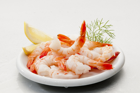 Steamed Jumbo headless shrimps with deli leaves and Lemon on white plate on white backgroundの写真素材
