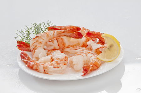 Steamed Jumbo headless shrimps with deli leaves and Lemon on white plate on white backgroundの写真素材