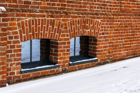 Two Windows in the basement in a brick wall. Snow on the streetの写真素材