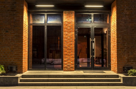 Two glass doors in a brick building in the nightの写真素材